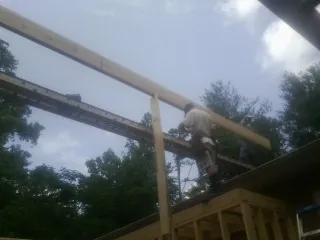 Carpenter setting a ridge beam over a new addition frame — Ice Dam Removal by Roofing Brothers in Northfield